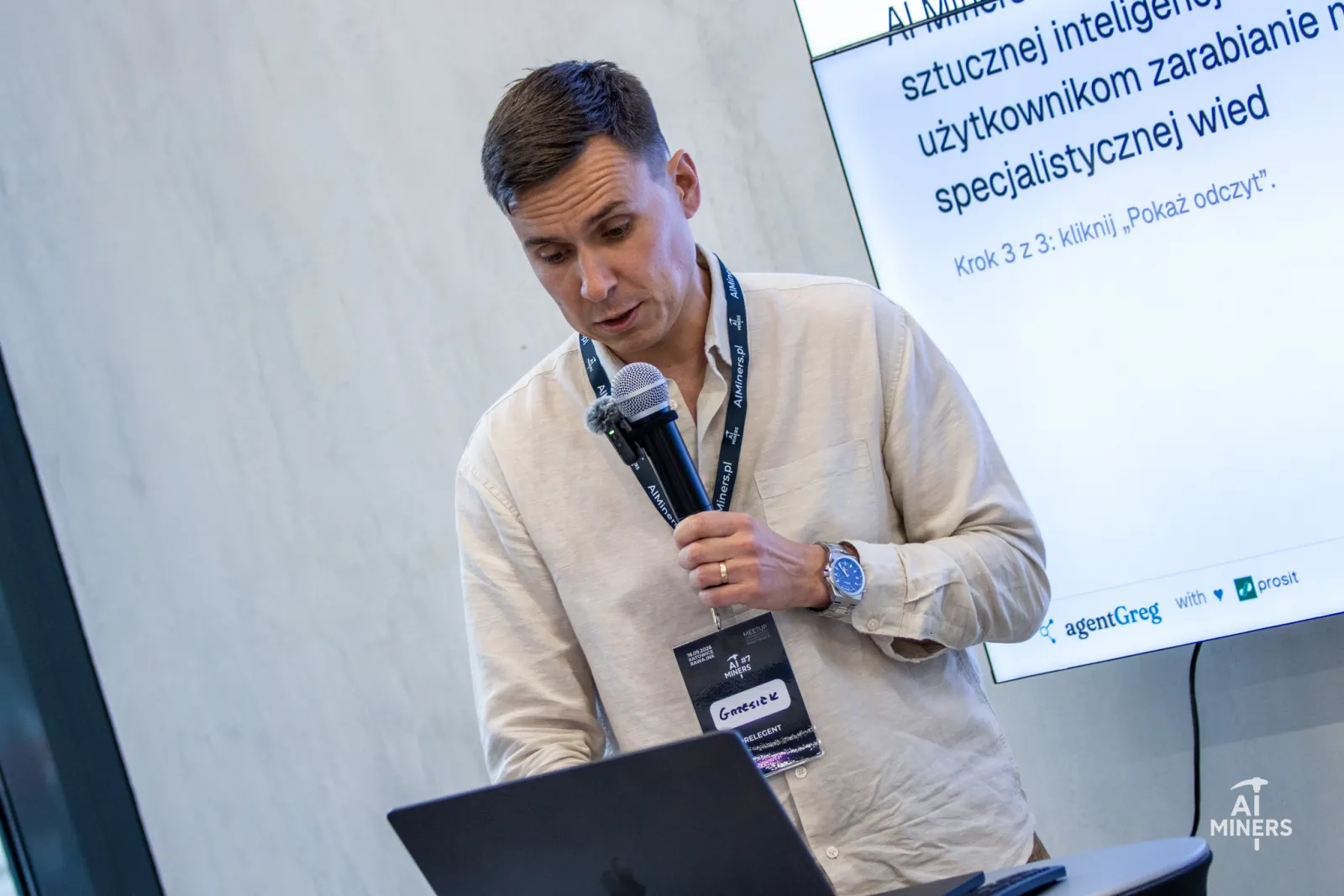 Grzegorz Brzezinka at the laptop with a microphone, the demo app on the screen behind him asking the audience to click &lsquo;Pokaż odczyt&rsquo;, show the reading.